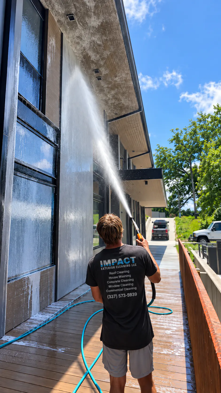 Evan Lyons washing the exterior of a commercial building in Lafayette, LA